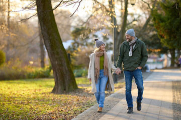 Fototapeta na wymiar Romantic couple enjoying a walk in the park holding hands