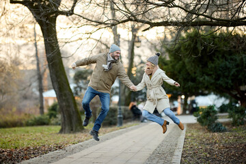 Affectionate smiling couple having fun jumping in the park