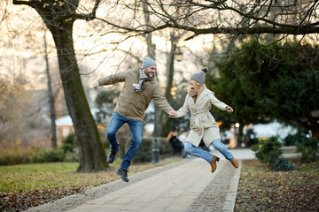 Obraz premium Affectionate smiling couple having fun jumping in the park