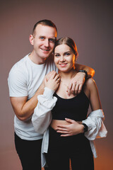 A couple in love in white shirts are hugging and enjoying each other. A stylish couple embraces each other on a white background. Happy family concept