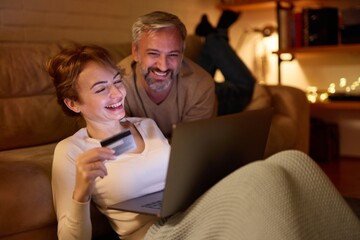 Mature couple doing online shopping using laptop and credit card at home