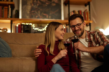 Romantic young couple relaxing at home and drinking red wine