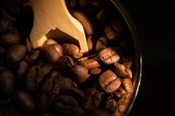 Coffee Beans display in dark background in dark wooden base with wooden spoon in glass mason jar