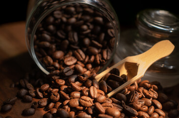 Coffee Beans display in dark background in dark wooden base with wooden spoon in glass mason jar