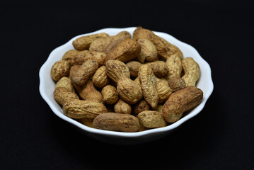 Groundnut. Unpeeled peanuts in a white plate. Peanuts in the peel.