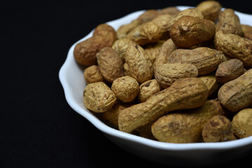 Groundnut. Unpeeled peanuts in a white plate. Peanuts in the peel.