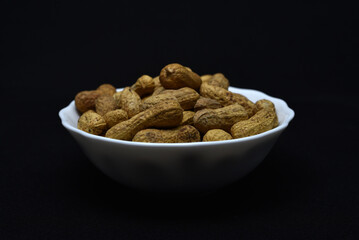 Groundnut. Unpeeled peanuts in a white plate. Peanuts in the peel.