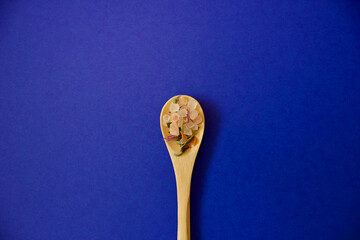 small wooden spoon with herbal salt on a blue background