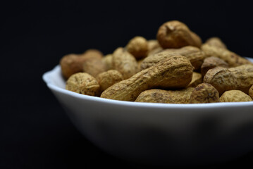 Groundnut. Unpeeled peanuts in a white plate. Peanuts in the peel.