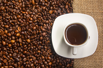 Coffee break background. Hot coffee in cup and roasted coffee beans on a wooden table. Copy space