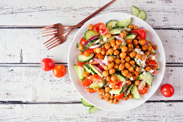 Healthy Mediterranean salad with chick peas. Top view table scene over a rustic white wood background.