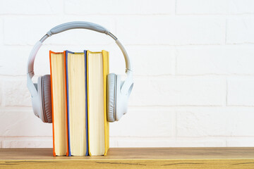 Fototapeta na wymiar Audio books concept. Wireless Headphones and color books at table.