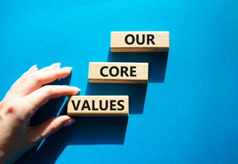 Our core values symbol. Concept words 'Our core values' on wooden blocks. Beautiful blue background. Businessman hand. Business and Our core values concept. Copy space.