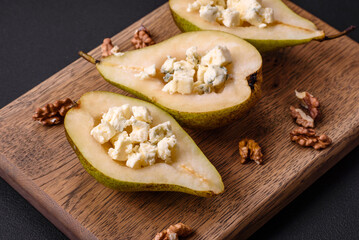 Delicious baked pear with dorblu cheese, walnut and honey on a textured concrete background