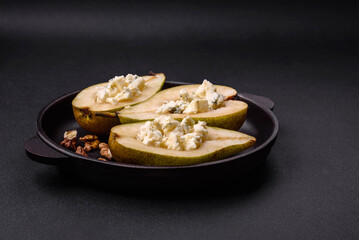 Delicious baked pear with dorblu cheese, walnut and honey on a textured concrete background