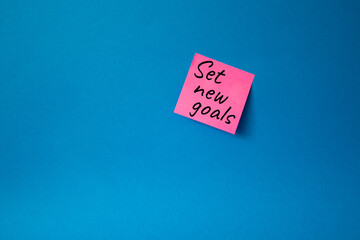 Set New Goals symbol. Concept words Set New Goals on pink steaky note. Beautiful blue background. Business and Set New Goals concept. Copy space.