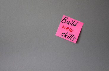 Build New skills symbol. Concept word Build New skills on pink steaky note. Beautiful grey background. Business and Build New skills concept. Copy space