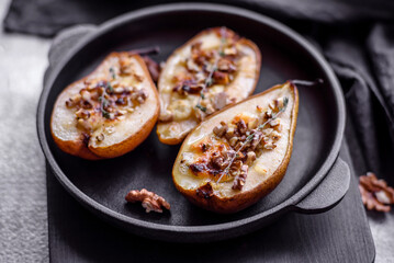 Delicious baked pear with dorblu cheese, walnut and honey on a textured concrete background