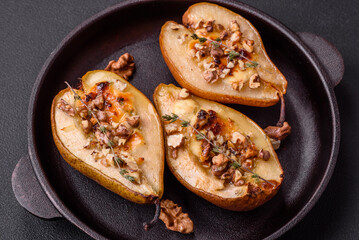 Delicious baked pear with dorblu cheese, walnut and honey on a textured concrete background