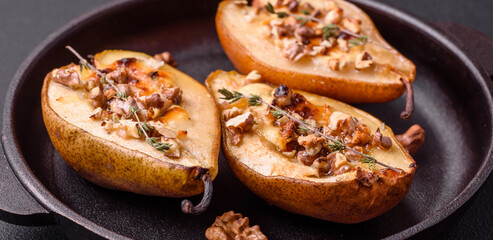 Delicious baked pear with dorblu cheese, walnut and honey on a textured concrete background