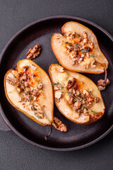 Delicious baked pear with dorblu cheese, walnut and honey on a textured concrete background