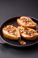 Delicious baked pear with dorblu cheese, walnut and honey on a textured concrete background