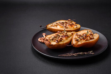 Delicious baked pear with dorblu cheese, walnut and honey on a textured concrete background