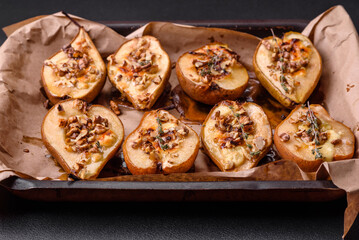 Delicious baked pear with dorblu cheese, walnut and honey on a textured concrete background