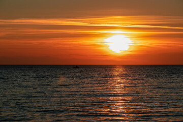 Small fishermen boat with scenic sunset view from Sveti Stefan at Adriatic Mediterranean Sea, Budva Riviera, Montenegro, Europe. Reflection of sun beams on water surface. Summer vacation atmosphere