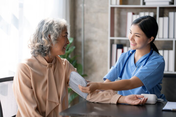 Fototapeta premium Asian female doctor measuring blood pressure for an elderly female patient.