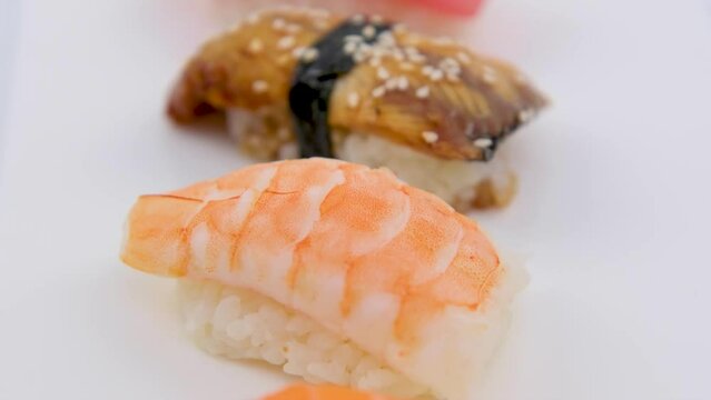 Sushi Set sashimi and sushi rolls served on white slate Tuna shrimp eel red fish salmon set of sashimi sushi with soy and chopsticks Asian Japanese food delicious restaurant beautiful serving