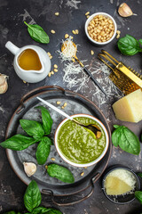 Obraz na płótnie Canvas Homemade pesto sauce and ingredients, Traditional Italian pesto recipe for pasta on a dark background, vertical image. top view. place for text