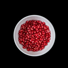 white plate with pomegranate seeds on a black background.
