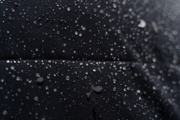 rain drops on the waterproof surface of black winter jacket 