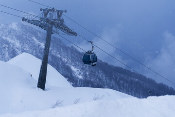 ski lift cable transporting skiers at mountain hills during snowing storm 