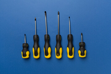 Screwdrivers on color background, top view
