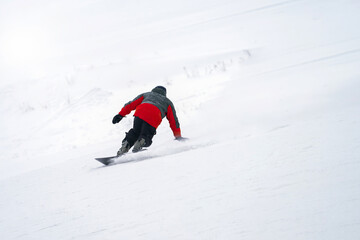 The ski slope. Snowboarder brakes on the snowy slope by touching the snow with his hand. Copy space.