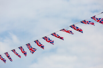 Looking up at Union Jack bunting against the sky - obrazy, fototapety, plakaty