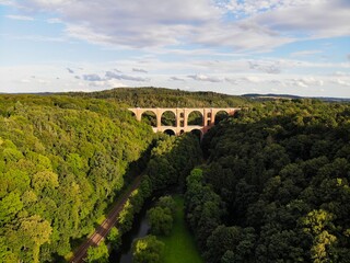 Drohnenaufnahme der Elstertalbrücke mit einem Fluss und Eisenbahnschienen bei Pöhl / Thüringen / Deutschland