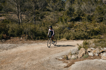 Fit male cyclist riding dirt trails on a gravel bike. A man riding a gravel bike on a gravel road in a scenic view with hills in Alicante region, Spain. Sports motivation.Gravel road in mountains.