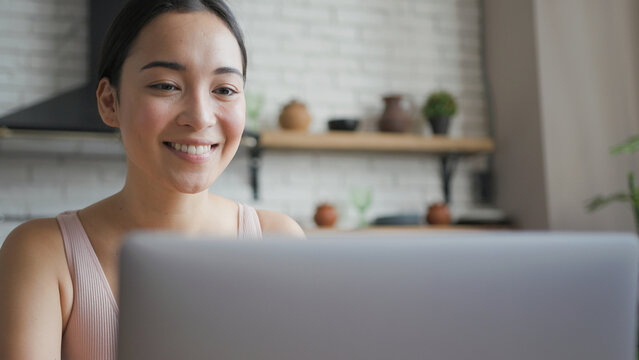 Close up portrait of healthy asian woman talking on a video call on laptop and smiling