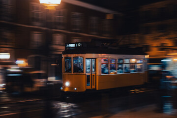 Naklejka na ściany i meble Lisbon tram in motion, panning, driving at night, blurry background