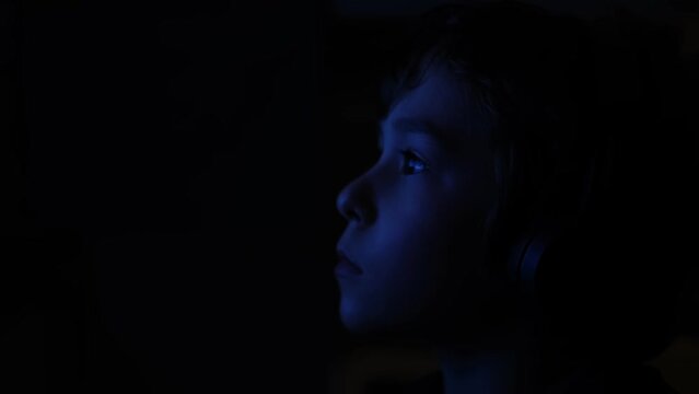 boy eyes staring at blue light at night. Child eyes looking at monitor. top view, barely visible silhouette