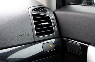 Car air vents close-up grille. Air ventilation grille with power regulator in light interior.