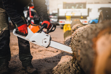 Cordless Chainsaw. Close-up of woodcutter sawing chain saw in motion, sawdust fly to sides. Chainsaw in motion. Hard wood working in forest. Sawdust fly around. Firewood processing.
