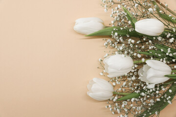 White tulips and gypsophila flowers bouquet on a beige background. Mothers Day, birthday...