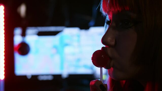 Sexy gamer girl sucks a lollipop and licks her lips