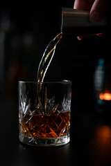 Pouring a glass of whiskey with a cocktail measurer in a fancy bar