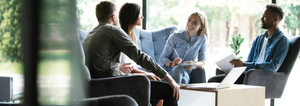 Group of young modern people in smart casual wear discussing business while working in the creative office