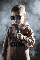 Chłopiec śpiewa do mikrofonu, refleksyjnie, nostalgicznie, przejmująco, smutne piosenki, dziecięca twórczość muzyczna - obrazy, fototapety, plakaty